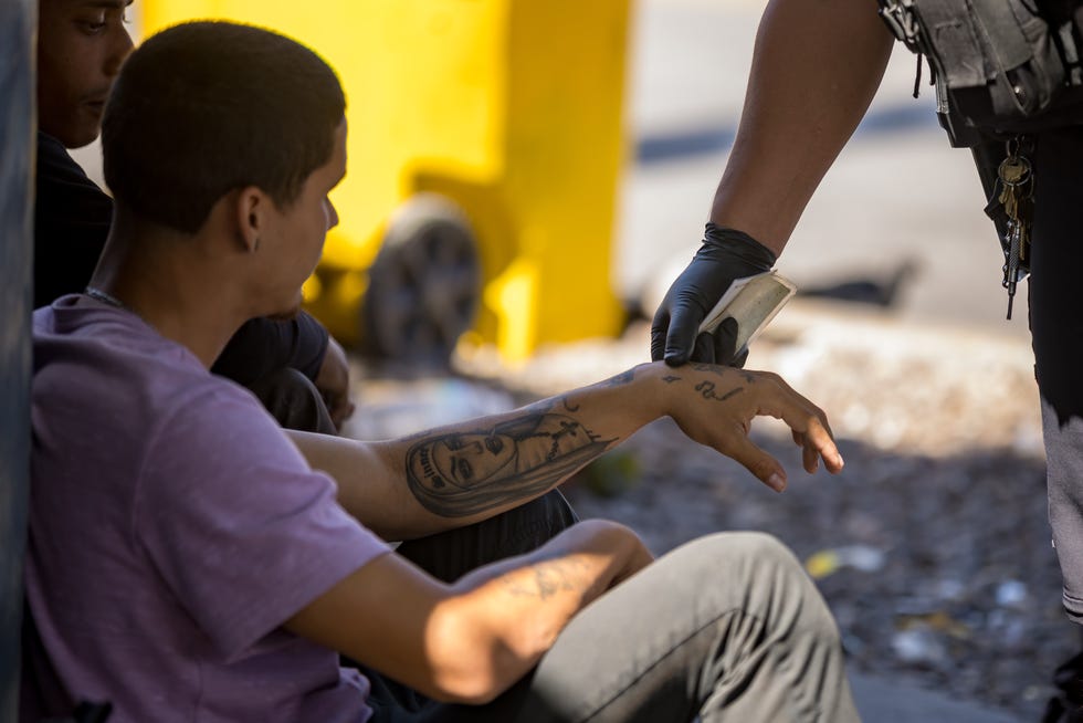 El Paso Police check Emerson Linares, a Venezuelan migrant's tattoos as they patrol the area where migrants are staying in front of Sacred Heart Church on Tuesday, Sept. 24, 2024.