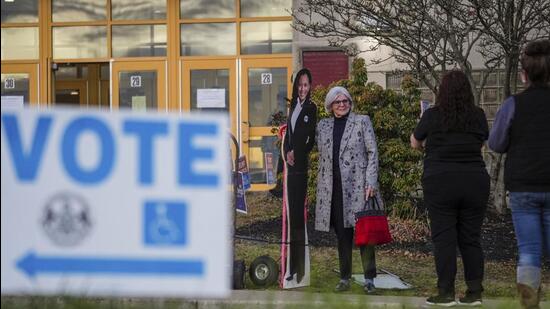 A voter poses for a cardboard cutout of Democratic presidential nominee Vice President Kamala Harris before voting opens at Scranton High School in Scranton, Pa., on Election Day, Tuesday (AP)