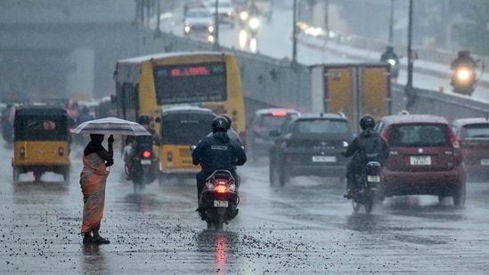 Commuters ride along a street amid rainfall in Chennai on November 12, 2024.(AFP)