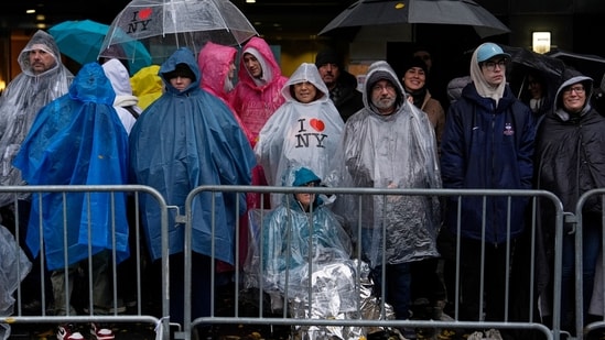 People stand in the rain along Sixth Avenue ahead of the start of the Macy's Thanksgiving Day Parade.(AP)