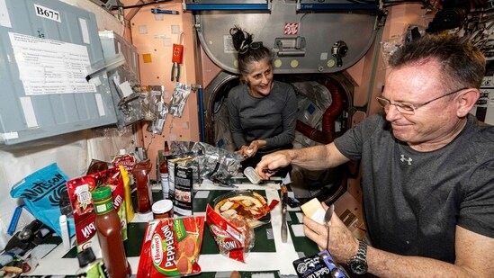 In this image released by NASA, NASA astronauts Suni Williams and Butch Wilmore, both Expedition 71 Flight Engineers, make pizza aboard the International Space Station's galley located inside the Unity module on Sept. 9, 2024. Items are attached to the galley using tape and velcro to keep them from flying away in the microgravity environment. (AP)