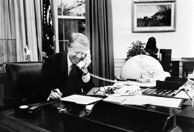 Photo taken in 1978 shows US President Jimmy Carter laughing during a phone call at his desk at the White House in the Oval Office in Washington.