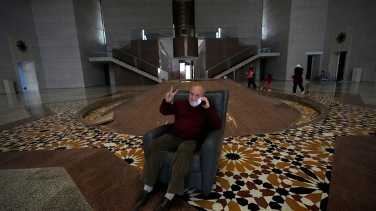 An old Syrian man posed for a picture on a chair flashing a victory sign inside the Syrian presidential palace. Storerooms and cupboards in the palace were also emptied out as citizens explored the palace under minimal armed presence(AP)