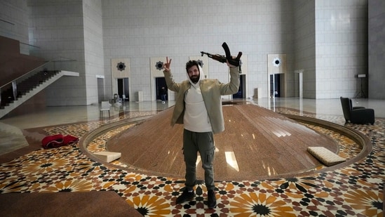 A man held an AK-47 and flashed the victory sign as he posed for a photo in a hall of president Bashar al-Assad's presidential palace.(AP)