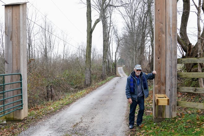 Chuck Klein stands next to the empty wood frame that once held a mailbox on the edge of his 130-acre property in Brown County, Ohio. Klein, 82, now drives almost a mile to pick up his mail because the Postal Service stopped delivering mail to his property after concluding the road was unsafe.