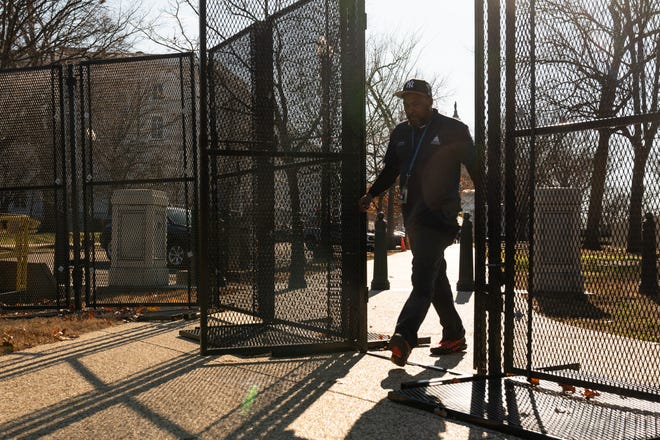 A man walks through temporary fencing that has been set up around the perimeter of the U.S. Capitol on Tuesday, Dec. 31, 2024.