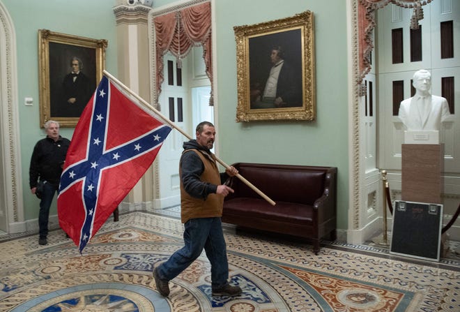 A supporter of US President Donald Trump carries a Confederate flag through the Capitol Rotunda on Jan. 6, 2021, after a violent mob disrupted certification of Joe Biden's 2020 election victory.